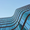 A modern building with flowing glass architecture against a clear sky.