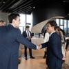 A group of business professionals shaking hands and engaging in conversation in a modern office environment.