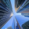 A dynamic upward view of towering skyscrapers converging into a clear blue sky.
