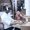 Two individuals wearing virtual reality headsets are engaged in a digital experience in a library.