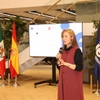 A speaker presents at an event featuring flags from Mexico and Spain in the background.