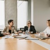 A group of five professionals in a meeting around a table in a modern office setting.