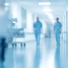 A blurred scene of healthcare professionals walking down a hospital corridor.