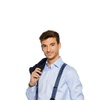 A young man in a blue shirt with suspenders holding a jacket over his shoulder.