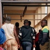 People are seen standing at the back of an open transport vehicle, possibly loading or unloading goods.