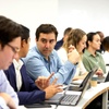 A group of people engaged in a discussion during a meeting with laptops in a modern setting.