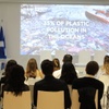 A presentation on ocean pollution taking place in a conference room, featuring flags of Finland and the USA.