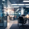 A blurred image of an office interior with a chair and desks in the background.