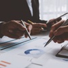 Business professionals analyzing financial charts and documents on a desk during a meeting.