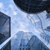 Looking up at a cluster of modern skyscrapers under a clear blue sky.