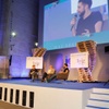 A discussion panel taking place at the Hay Festival, featuring three speakers on stage.