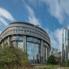 A modern architectural view of a glass building with greenery in the foreground.