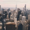 A panoramic view of a city skyline filled with tall buildings under a cloudy sky.