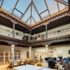 A modern open workspace featuring a lofted design with wooden beams and a glass roof.