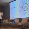 A woman is presenting at a conference with a visual aid explaining best practices for managing projects successfully.