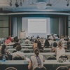 A large audience attending a presentation in a conference room.