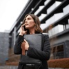 A professional woman holding a briefcase speaks on her phone outside a modern building.