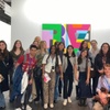 A group of young people posing together in front of colorful artwork at an exhibition.