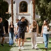 A group of young people walking together in a lush garden setting.