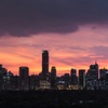 A city skyline silhouetted against a vibrant sunset.
