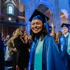 A joyful graduate wearing a blue cap and gown smiling at a ceremony.