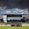 A group of people sitting on the grass in front of a modern glass building with a unique architectural design.