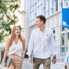 Two young adults walking and laughing together on a university campus, one of them holding books.