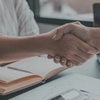 what seems to be a business woman and a business man shaking hands denoting for the viewer they reached an agreement