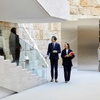 People in a modern corporate building interior, featuring a sleek design with marble and minimalist elements.