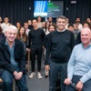 A group of people posing for a photo in a classroom setting with a presentation screen in the background.