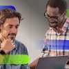 Two men, one looking at a tablet and discussing something with a coworker.