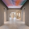 A modern art gallery hallway with colorful ceiling lights and artwork displayed on the walls.