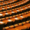 A large hall filled with rows of empty desks and chairs.