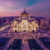A stunning view of a historic building illuminated at dusk surrounded by vibrant city life.