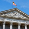 The image depicts the façade of the Congress of Deputies in Spain, featuring classical architecture and a Spanish flag.