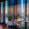 A meeting taking place in a modern office with a cityscape reflection in the windows.