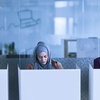 Three women are working quietly in a modern office space with cubicles.
