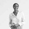 A black and white image of a smiling woman in a white blouse and light trousers.