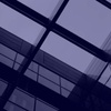A view of a modern glass ceiling with geometric lines and reflections.