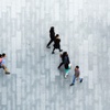 Aerial view of multiple people walking on a patterned pavement.