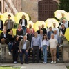 A group of people holding yellow umbrellas posing together on outdoor steps.