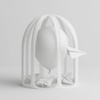 A white balloon enclosed in a cage with paper airplanes below it.