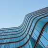 A modern building with wavy glass windows under a clear blue sky.