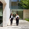 Two women walking together in a modern outdoor setting.