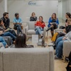 A diverse group of people sitting in a circle engaged in a discussion in a modern indoor setting.