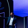 A man presenting on stage at an event with IE University branding in the background.