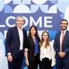 Five professionals standing in front of a blue 'IE University' welcome banner.
