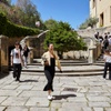 A group of people walking on stone steps in a sunny courtyard.