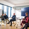 A group of people are engaged in a discussion in a modern office setting.