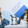 Two women are seated in a professional discussion setting with microphones.